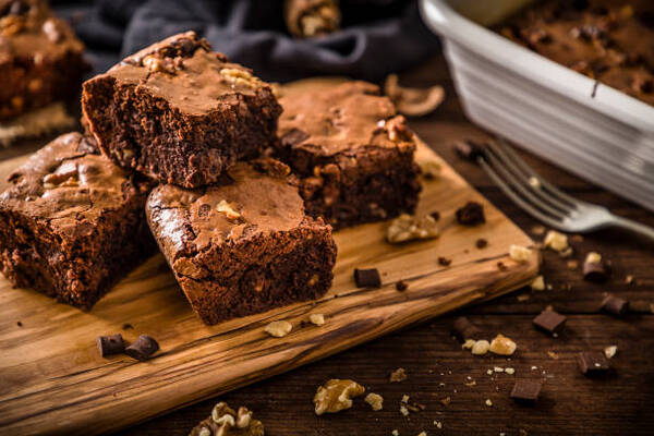 Quick and Simple Low-Carb Brownies You’ll Want Every Day 9 Homemade chocolate brownie slices on a wooden cutting board with crumbs and nuts
