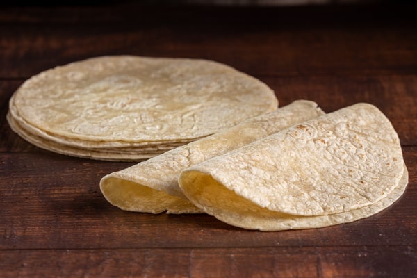 Are Corn Tortillas Keto or Just a Carb Trap? 3 A stack of corn tortillas with a few folded ones placed on a wooden surface