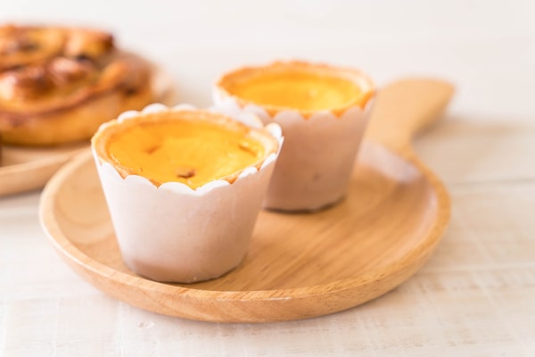 Keto Egg Cups: A Quick Breakfast Solution 5 Two freshly baked keto egg cups in paper liners placed on a wooden serving plate