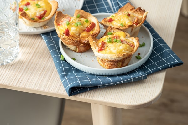 Keto Egg Cups: A Quick Breakfast Solution 7 Keto egg cups made with cheese, bacon, and green onions served on small white plates over a blue checkered napkin