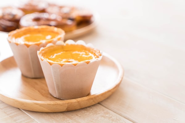 Keto Egg Cups: A Quick Breakfast Solution 8 Two golden keto egg cups in paper liners placed on a round wooden serving plate