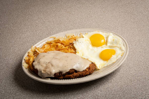 Perfect Keto Chicken Fried Steak with a Creamy Gravy Twist 8 A plate of chicken fried steak with gravy, fried eggs, and hash browns