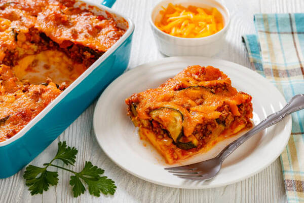Hearty Hamburger Zucchini Casserole for the Whole Family 3 A slice of ground beef casserole with zucchini and melted cheddar cheese in a baking dish