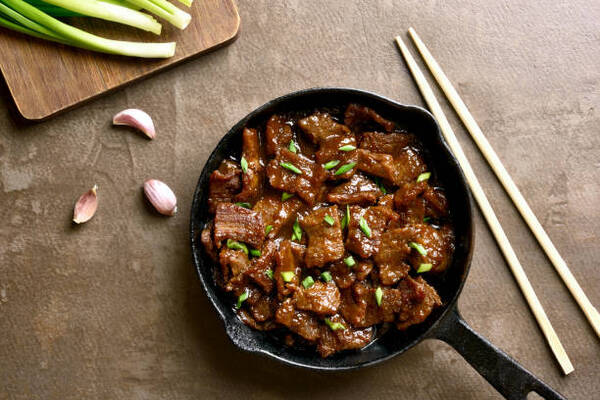 Easy Mongolian Beef Recipe You Can Make at Home Tonight 3 Mongolian beef in a pan with garlic and scallionsMongolian beef stewed in Asian style sauce in a pan with garlic and scallions