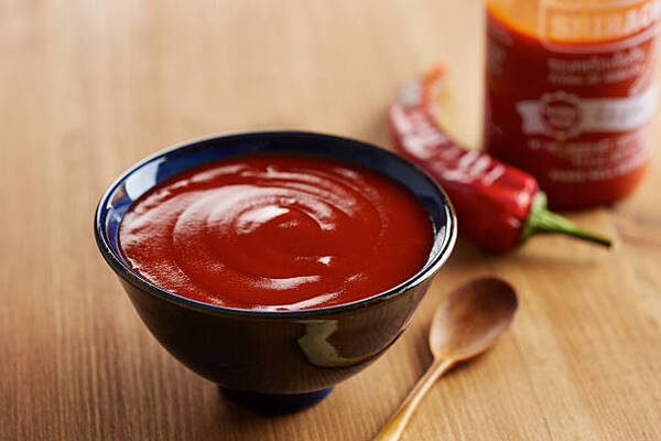 Bowl and bottle of sriracha sauce with red chili