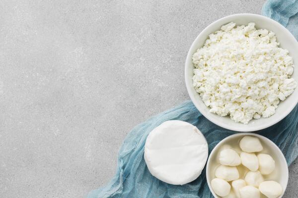 Low Carb Cottage Cheese: Best Brands and Ways to Enjoy 4 An overhead shot displays three types of fresh cheese, arranged on a blue cloth against a grey stone background.