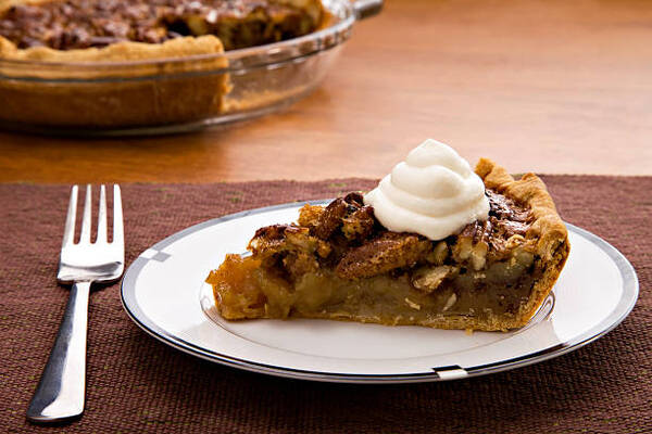 A slice of fresh homemade pecan pie with whipped cream on top
